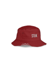 A red bucket hat featuring the Stōk logo in white lettering on the front. The image hints at the other side of the bucket hat resembling a festive, winter theme.