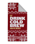 A red towel for Stōk cold brew coffee featuring a holiday-themed design. The sign has a red background with white knitted patterns resembling snowflakes and festive decorations. The large text in the center reads ‘EAT DRINK COLD BREW AND BE MERRY,’ with ‘Stōk’ logo displayed at the bottom